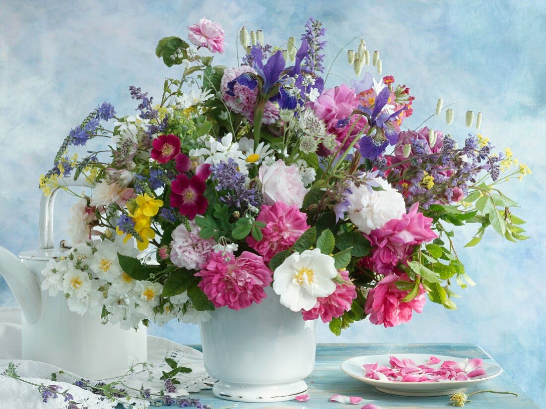 Colourful bouquet in white vase next to teapot