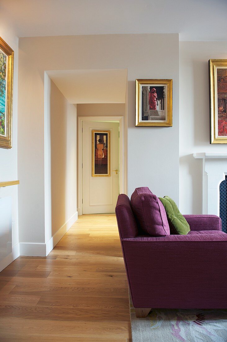 Violettes Sofa im Wohnraum mit offenem Durchgang und Blick in Flur