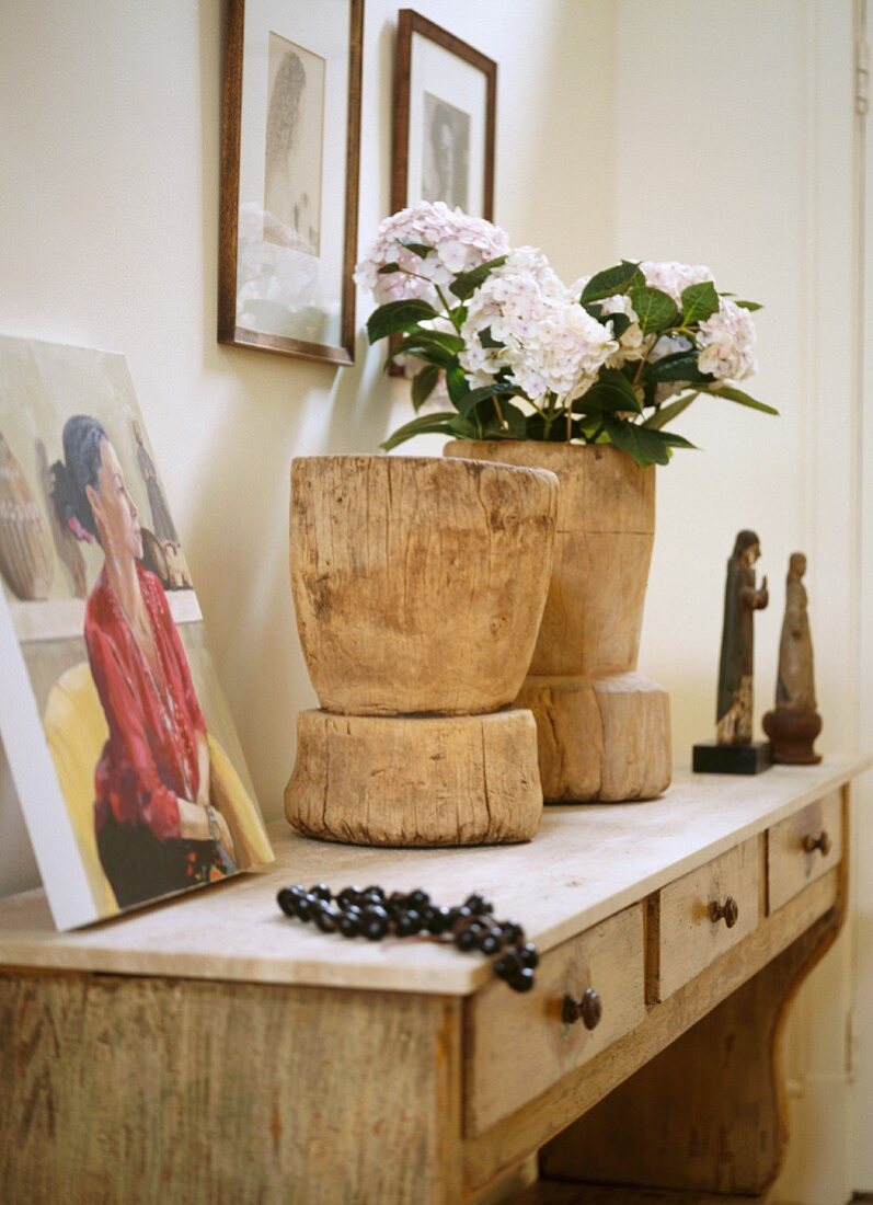 Rustikale Holzbehälter mit Blumen auf Wandtisch mit Schubladen