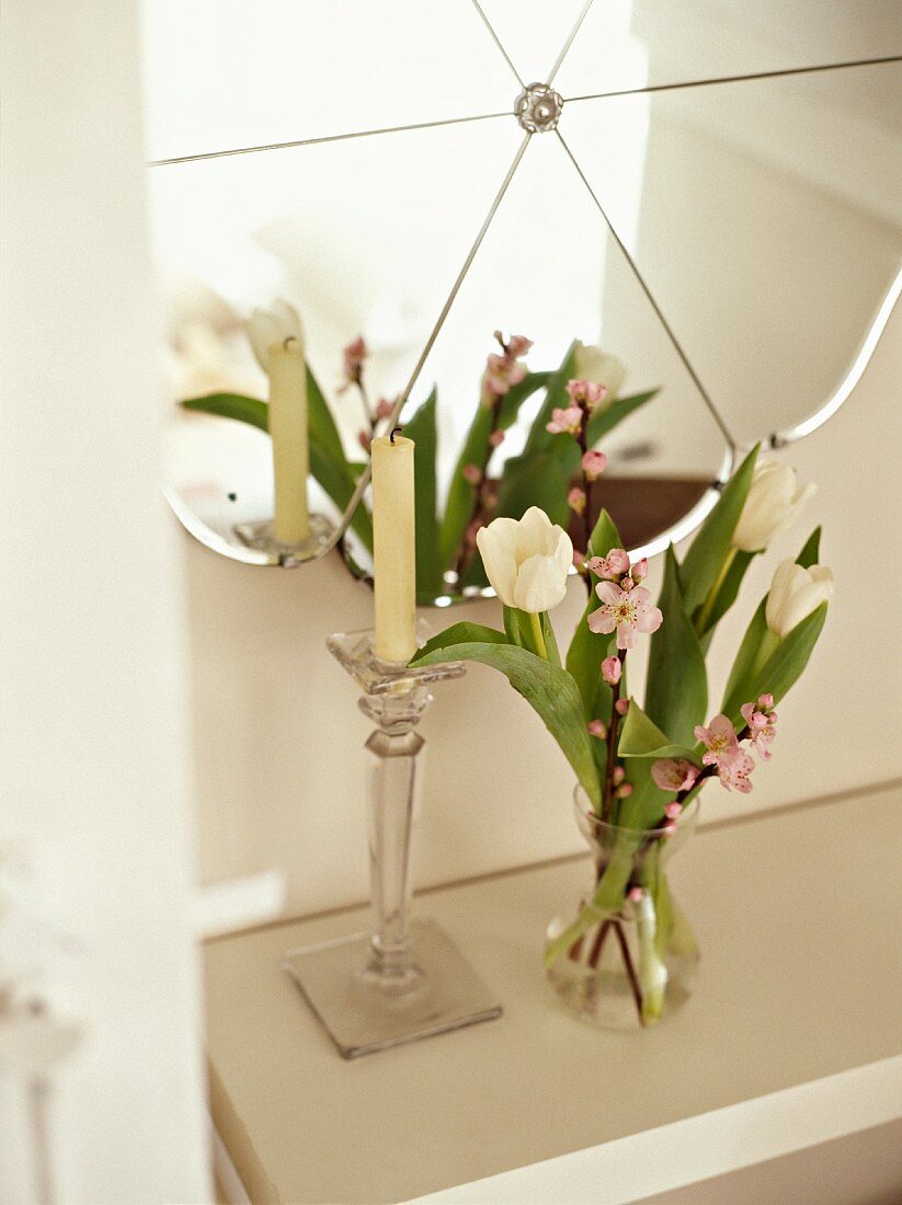 Weisser Tulpenstrauss und Kerzenständer auf weisser Ablage vor Wandspiegel