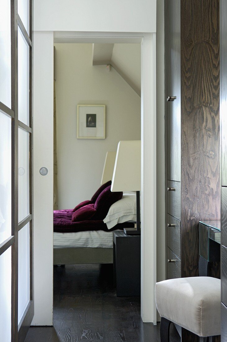 Vorraum mit Schrankeinbau und Blick durch offene Schiebetür auf modernes Bett