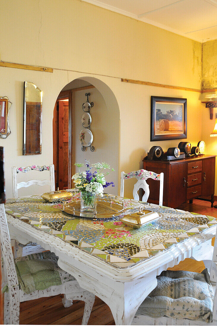 Mixture of styles in dining room with large mosaic table in foreground