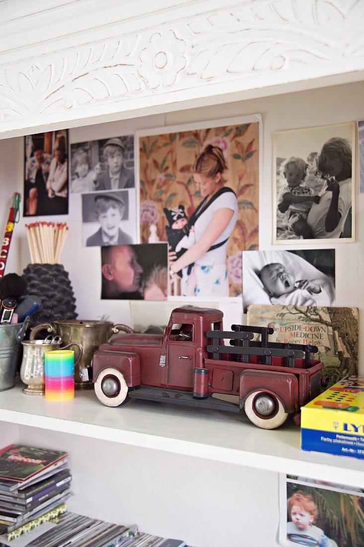 Vintage Spielzeugauto auf Regal und Familienphotos an Rückwand des Regalschrankes