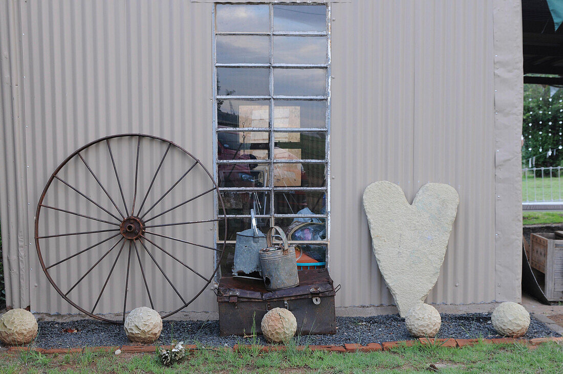 Sandstone heart and spheres and rusty wagon wheel against house facade