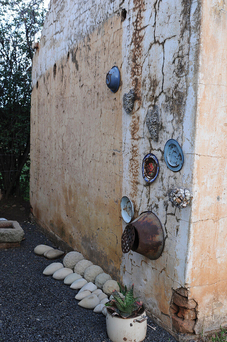 Old pots and stones against exterior wall of house