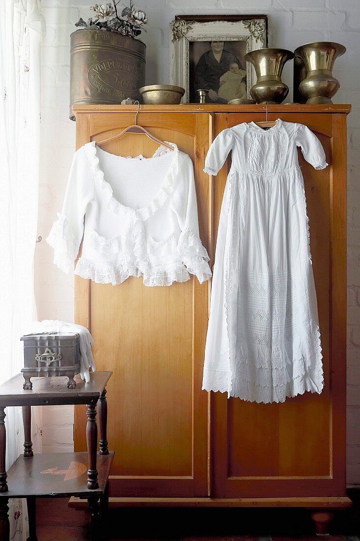 weiße Damenbekleidung auf Kleiderbügel vor Kleiderschrank hängend