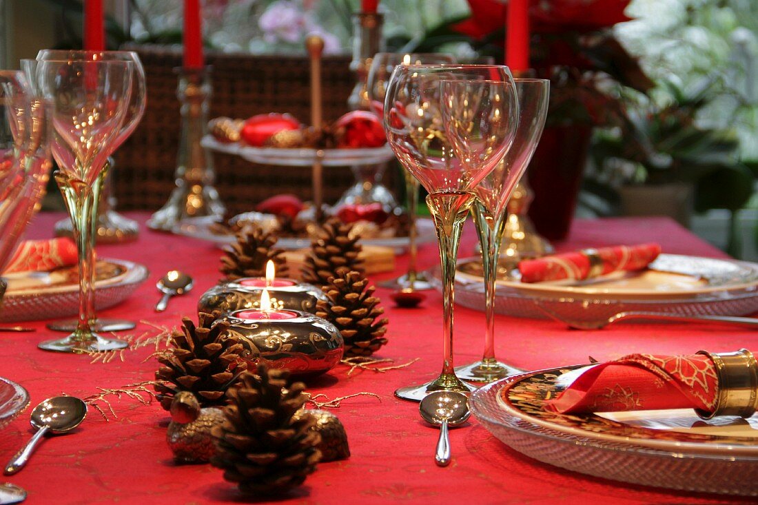 Table set and decorated in red for Christmas with pine cones and silver fern fronds