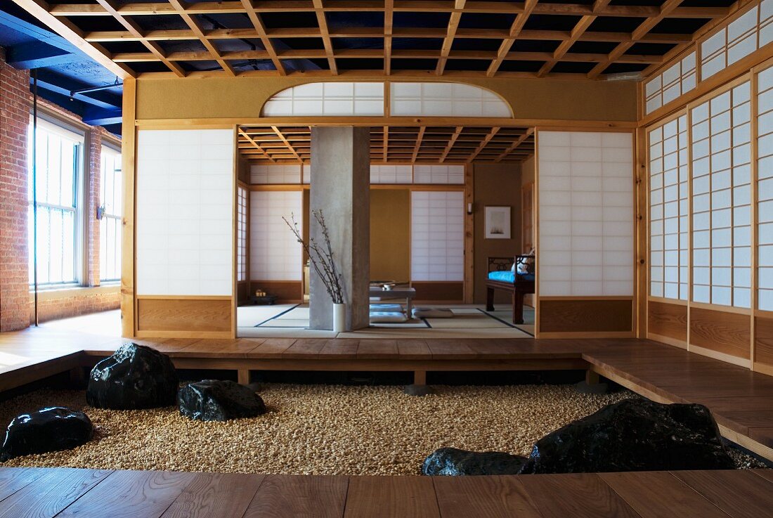 Vorraum mit Podest und gekiestem Boden vor offenem Meditationsraum mit japanischen Wänden in Industriehalle