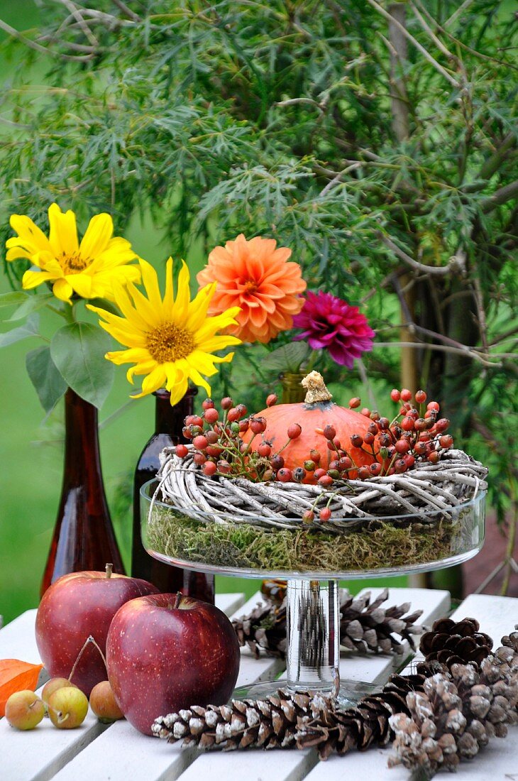 Herbstliche Tischdeko mit Kürbis, Dahlien, Äpfeln und Zapfen