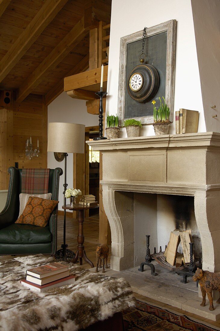Sitting area with antiques in front of an fireplace with an old stone surround in a renovated country home