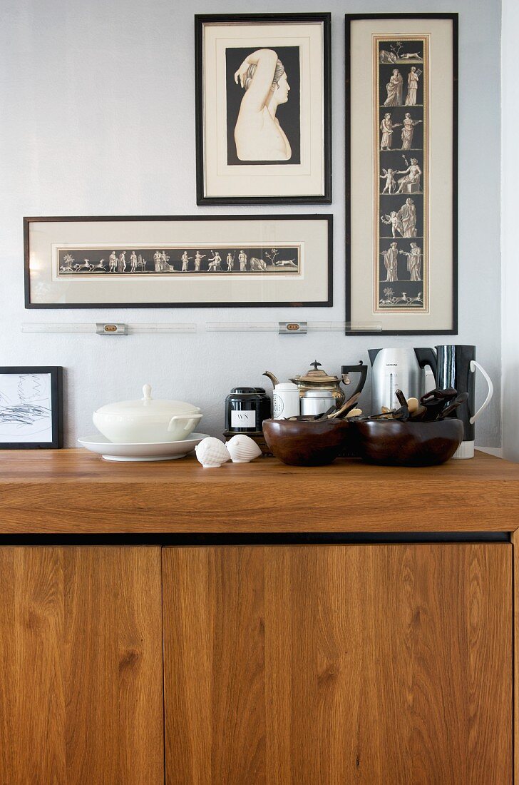 Holz mit dunklen Accessoires - gerahmte Drucke über zeitgenössischer Küchenzeile aus Edelholz mit abgestellten Kannen und Schalen
