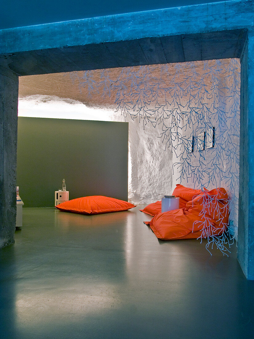 Orange Sitzsäcke auf poliertem Estrichboden in kellerartigem Wohnraum