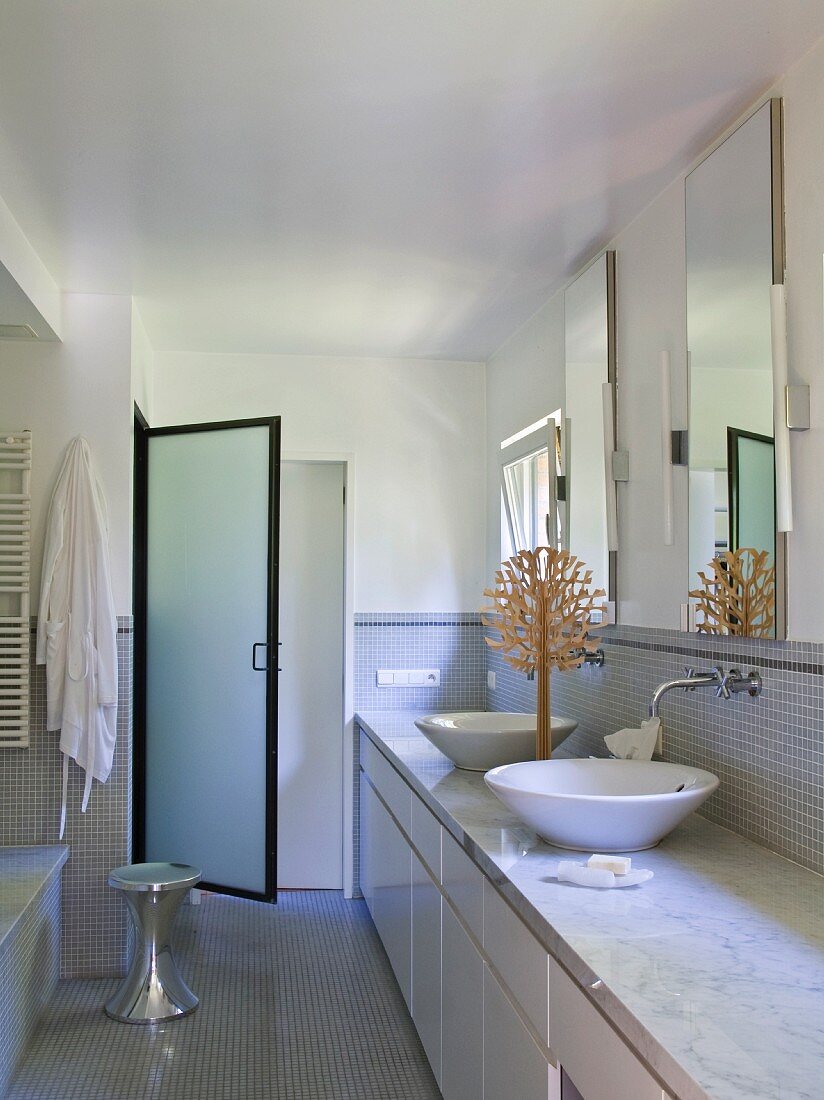 Designer bathroom with two wash basins on washstand and glass door leading to shower area