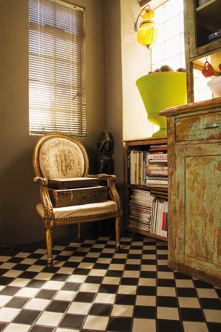 Corner with kitchen buffet in the shabby look, book shelves and a gilt baroque chair