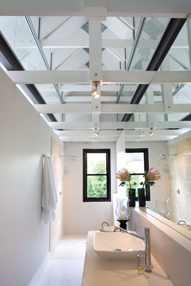 Spiegeleffekte in schmalem Bad mit modernem Waschtisch und Duschbereich unter der offenen Dachkonstruktion
