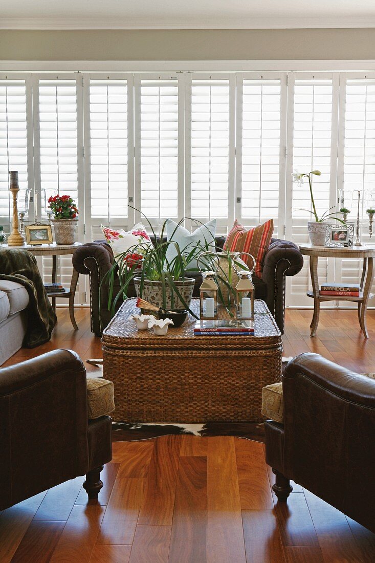 Light and bright living room with a large bank of windows, wicker table and animal skin rug