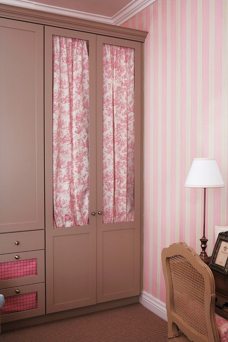 Clothes closet with door drapes - their color enhances the striped pattern of the wallpaper