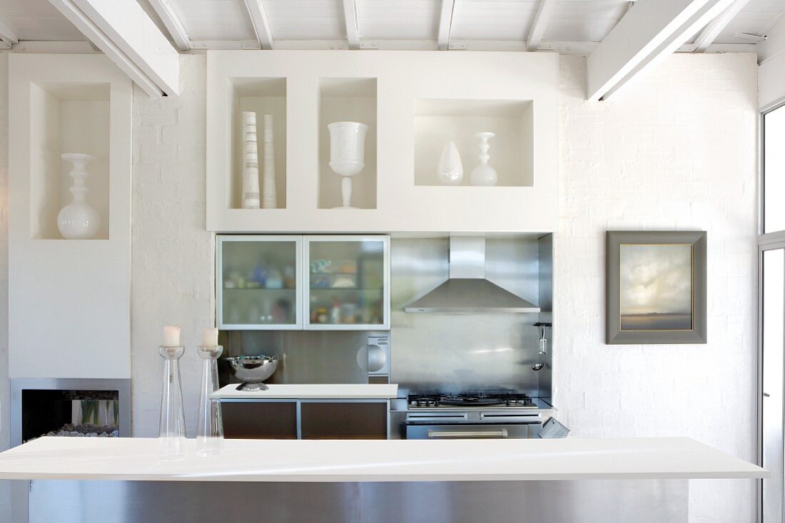 Tisch vor Wand mit gemauerten Regalöffnungen und Mini Küchenzeile