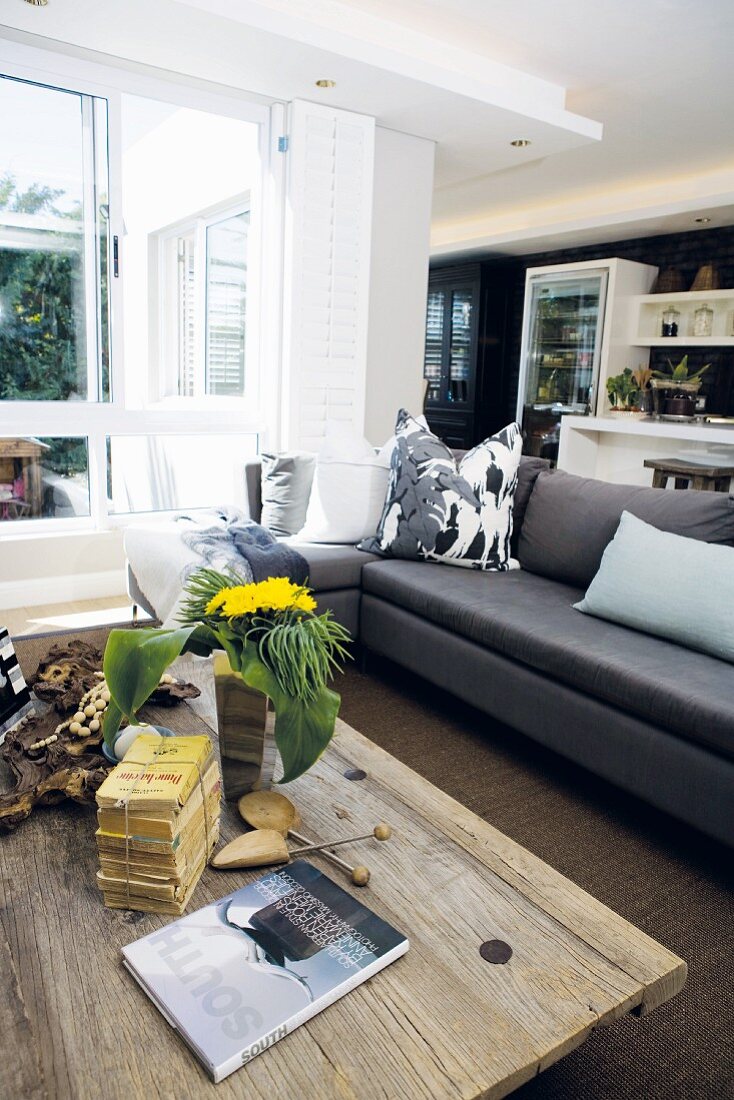 Rustikaler Couchtisch aus Holzbohlen und moderne Couch in offenem Wohnraum