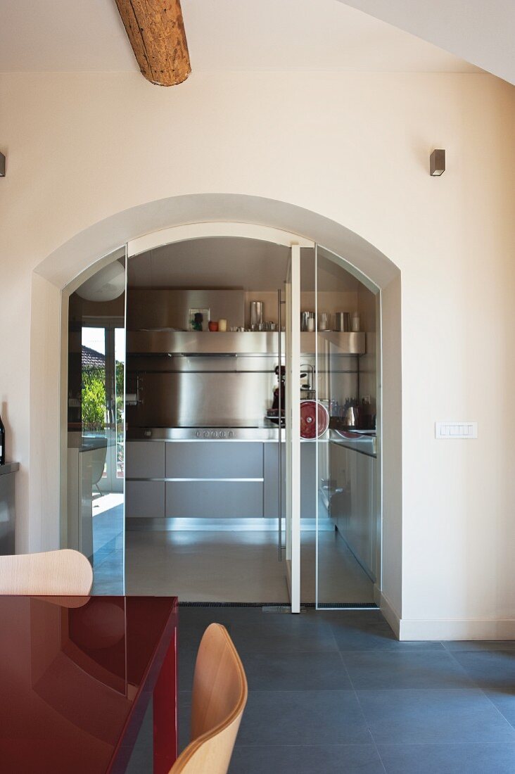 Round archway with open glass door and view into designer kitchen