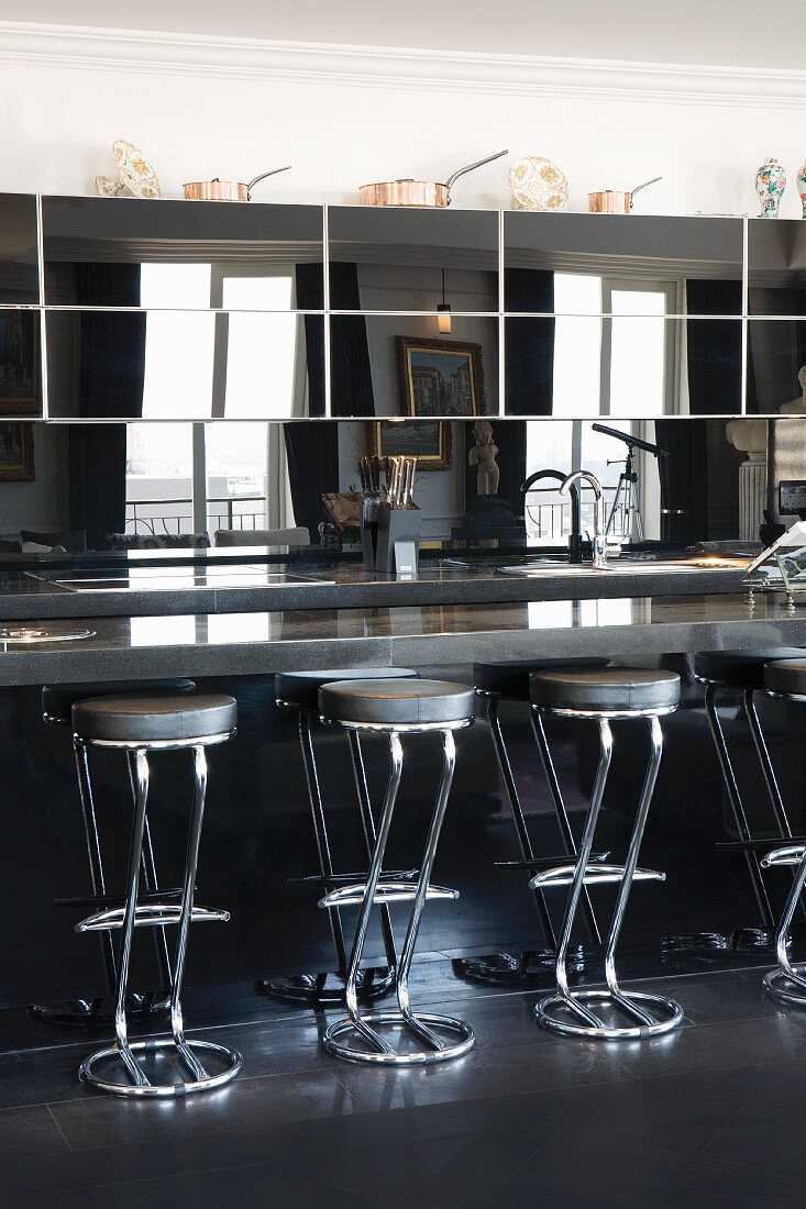 Round tube chrome bar stools at a modern kitchen counter with reflective top units