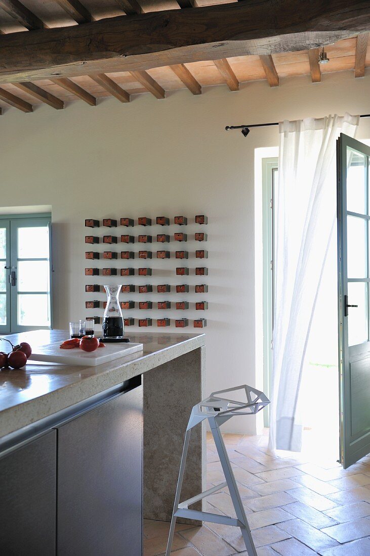 Küchentheke mit Designer Barhocker vor offen stehender Terrassentür