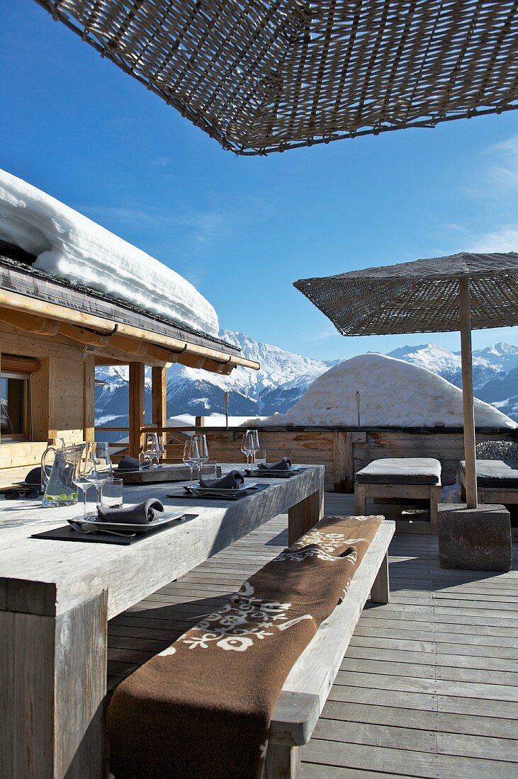 Set table on the wooden terrace of a hut in a snowy mountain landscape