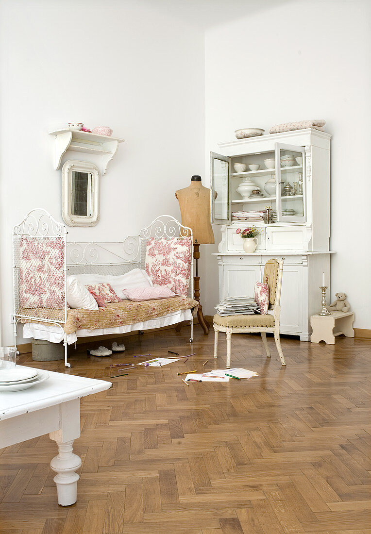 Kinderbett aus Eisen mit französischem Quilt und weiße Anrichte in Zimmerecke einer Altbauwohnung