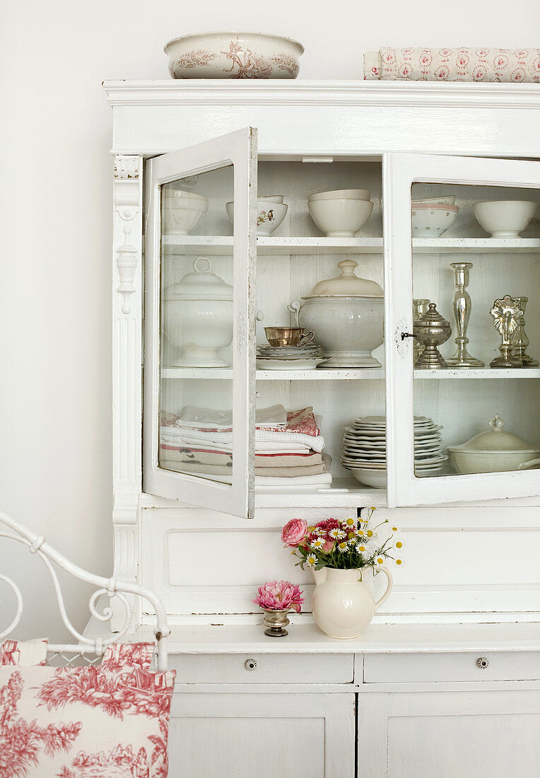 White, vintage dresser with open doors and view of crockery