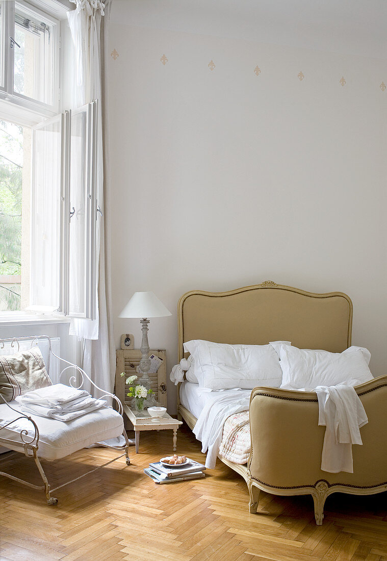 Französisches Corbeille-Bett und Eisensessel auf Fischgrätparkett im Schlafzimmer einer Altbauwohnung