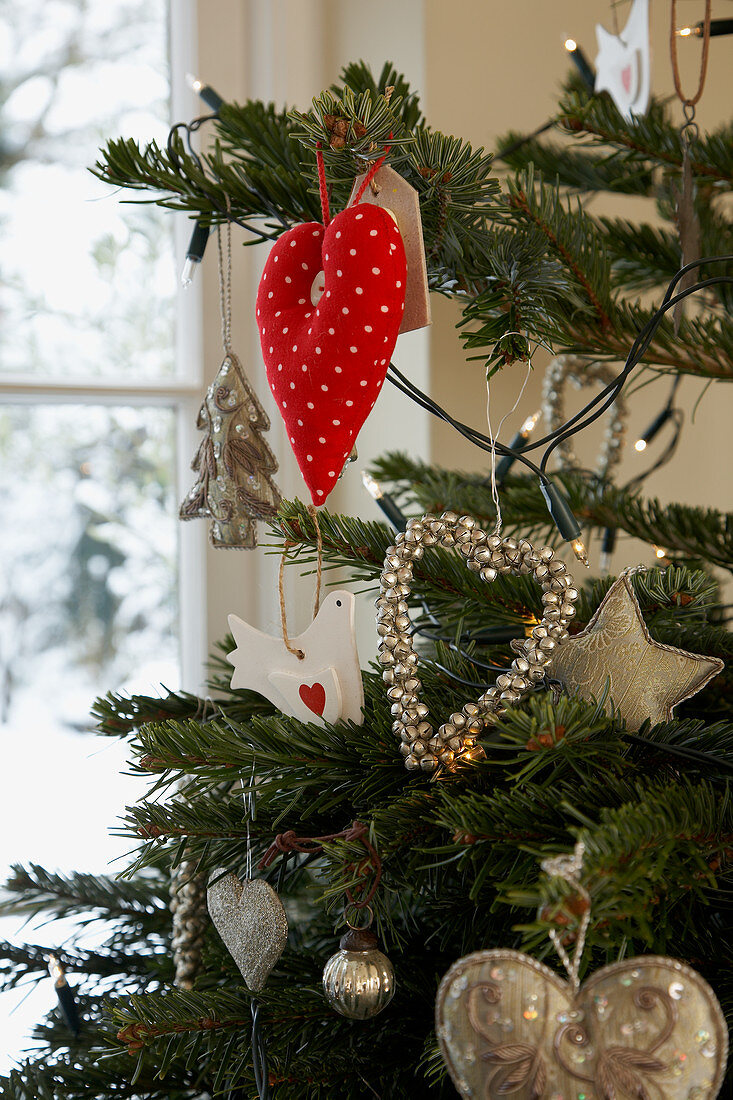 Mit verschiedenen Anhängern in Herzform und Lichterkette geschmückter Weihnachtsbaum