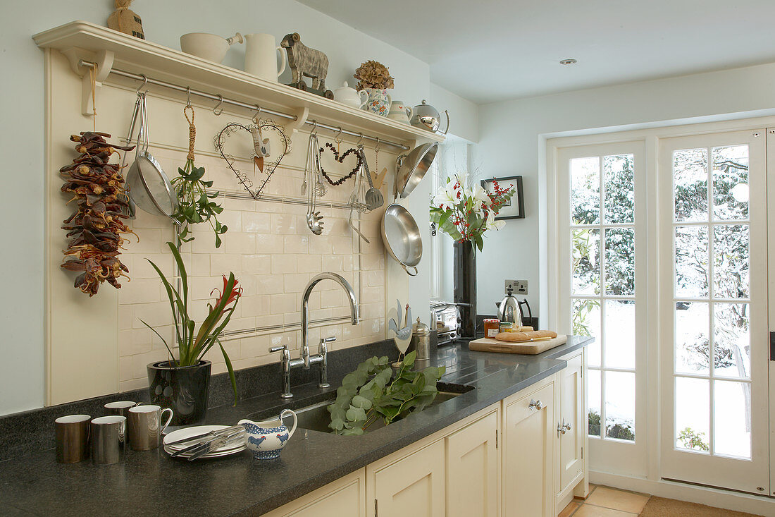Cremefarbene Landhausküche im Shaker-stil mit romantischer Dekoration über Arbeitsplatte mit dunkler Natursteinoptik
