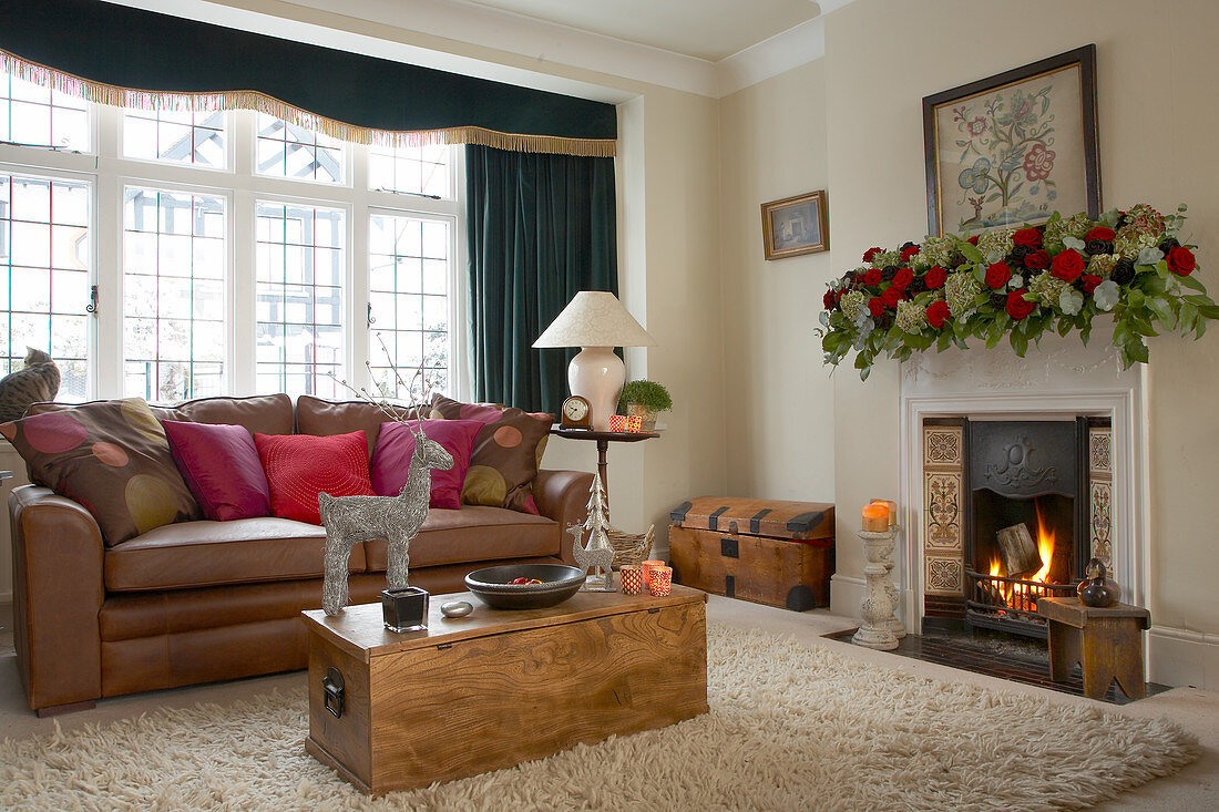 Klassisches Wohnzimmer, weihnachtlich geschmückt mit stilisiertem Hirsch auf einem Truhentisch und Rosengirlande auf dem Kaminsims