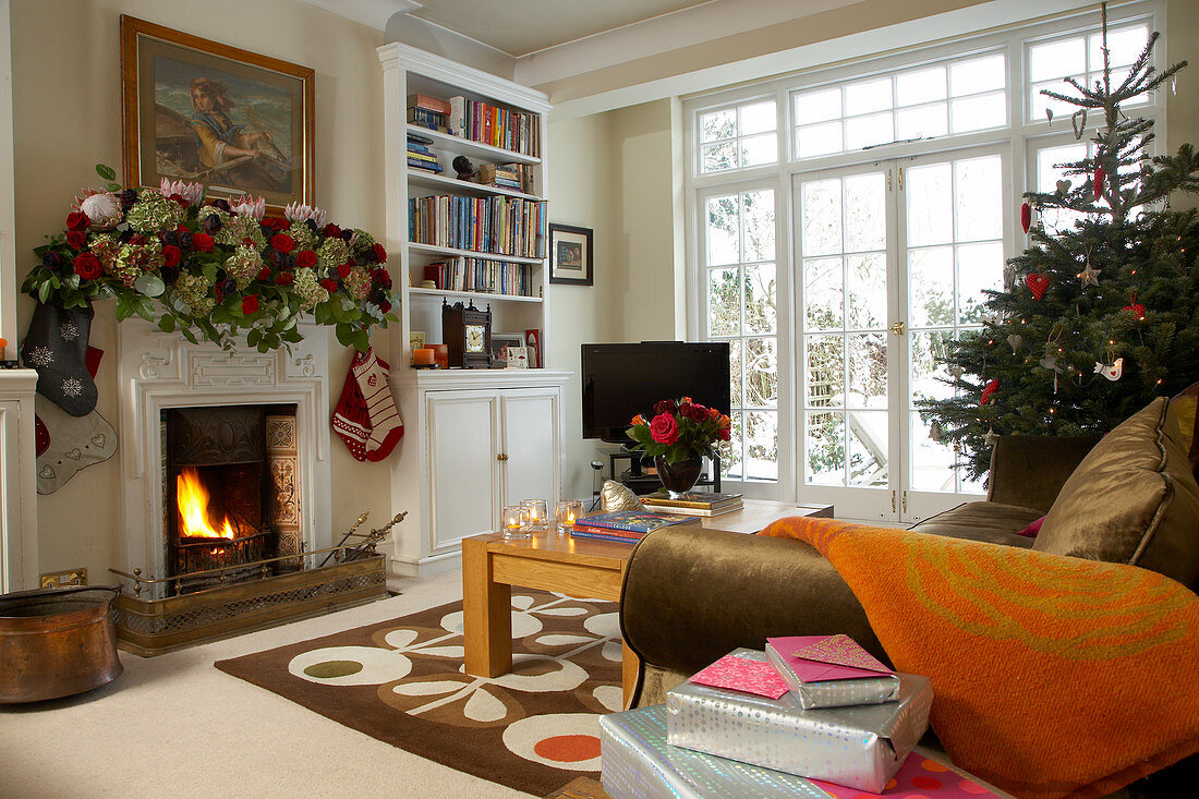 Living room in English country house with eclectic furnishings and festively decorated with fir tree and garland of roses