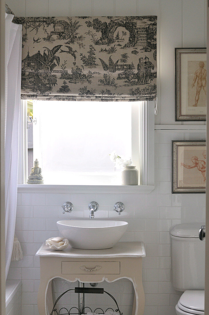 Wash basin on top of antique-style cabinet below window; Roman blind printed with Chinese motifs