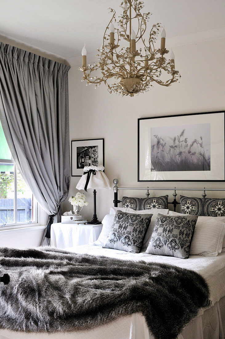 Weisses Landhaus-Schlafzimmer mit grauen Accessoires und goldfarbenem Kronleuchter