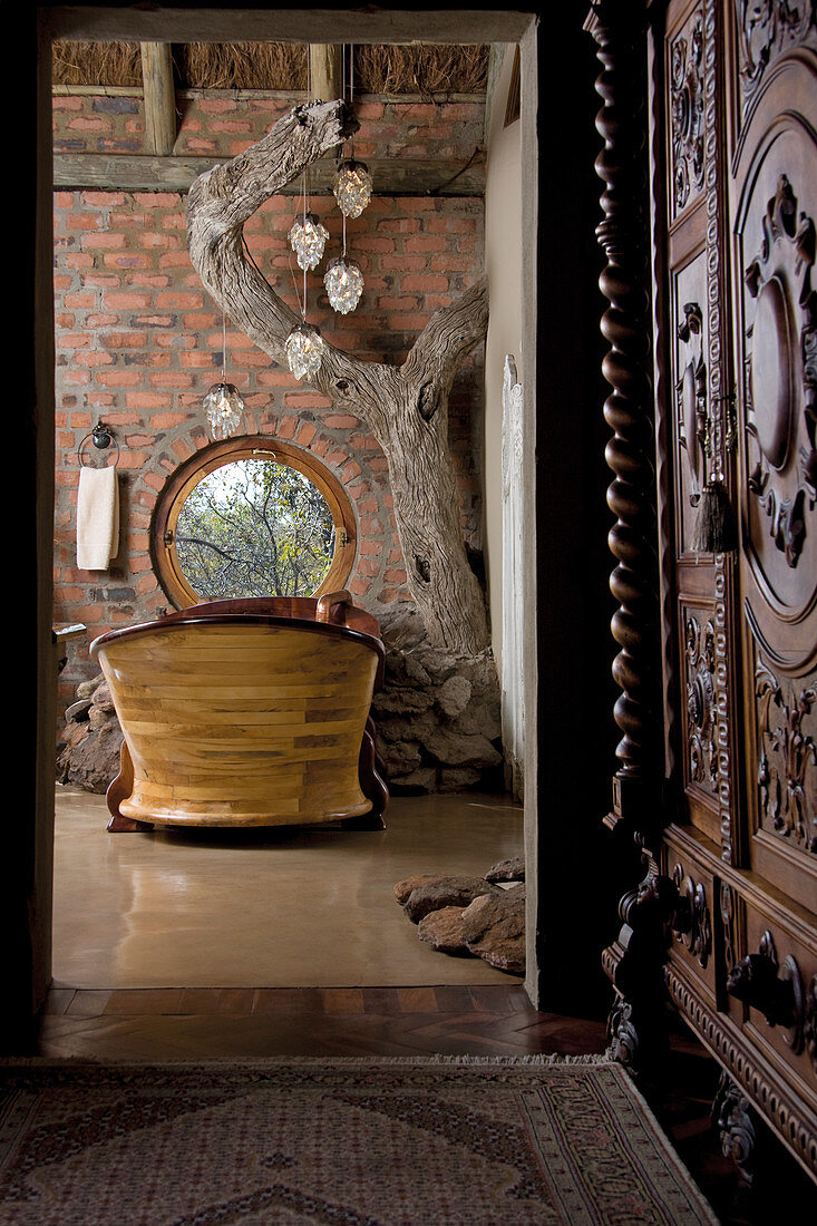 Blick durch offene Tür auf Badewanne aus Holz am Fenster