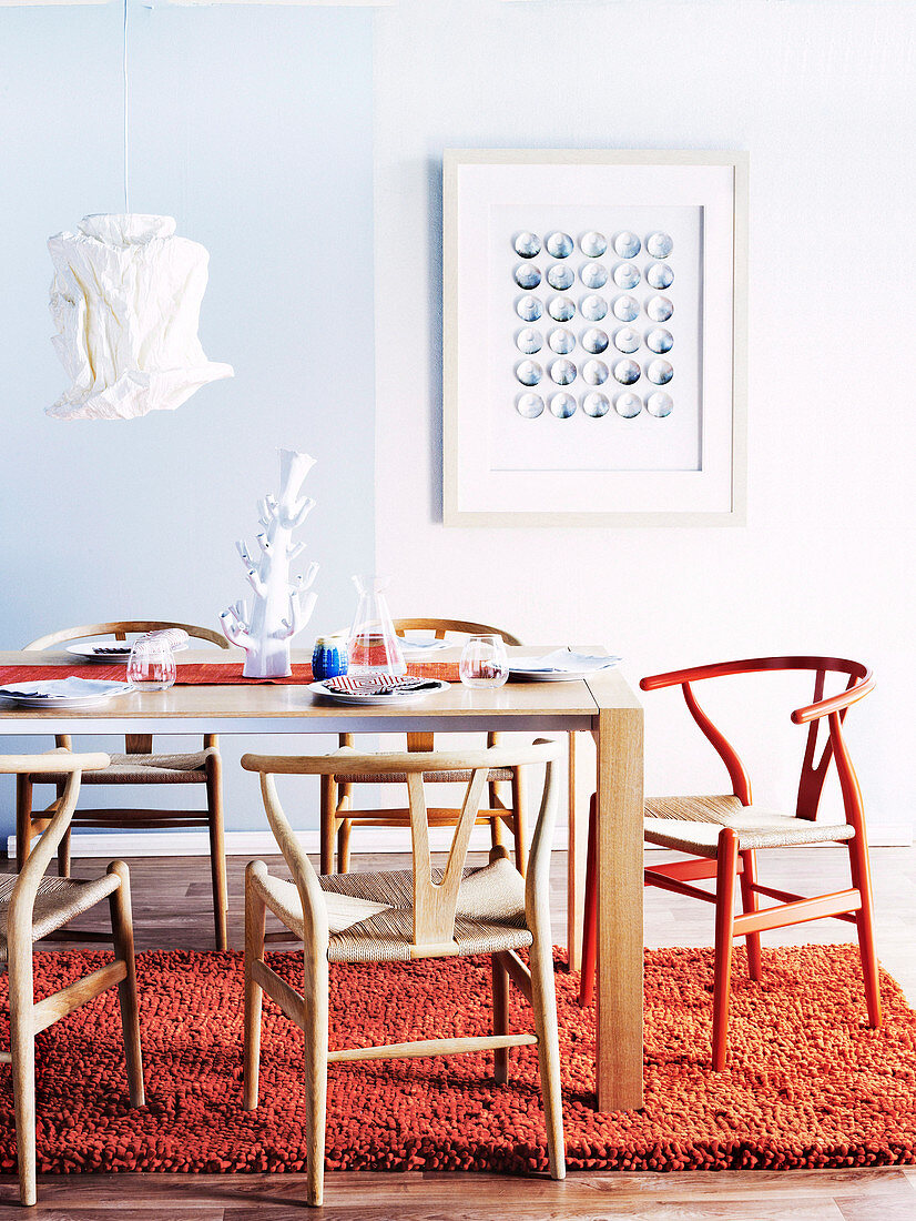 Tisch mit Designer-Stühlen, Hängelampe mit Papierschirm und Wollteppich in einem Esszimmer