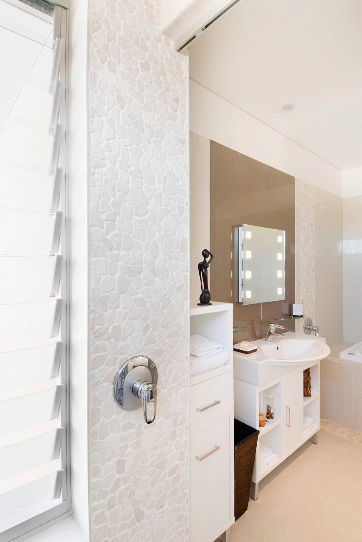 Small, polygonal tiles on wall with shower fittings in modern bathroom