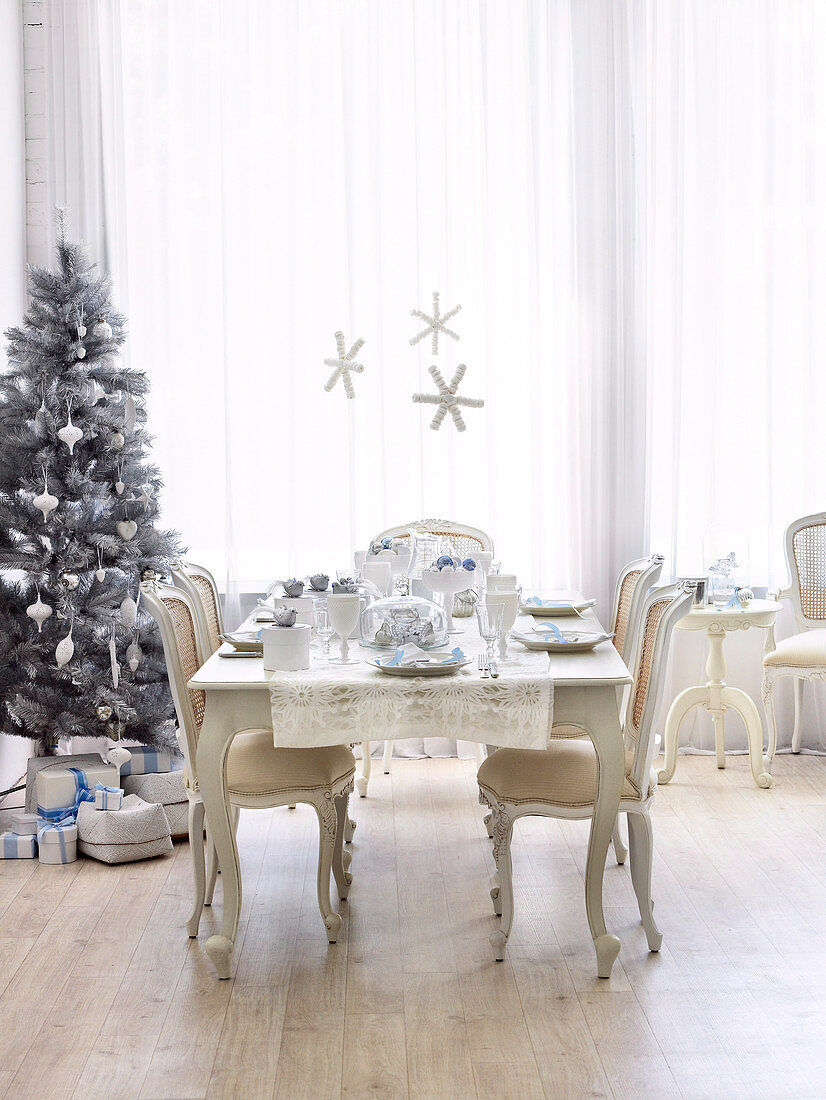 Stühle und Tisch im Rokokostil mit Gedecken vor Weihnachtsbaum