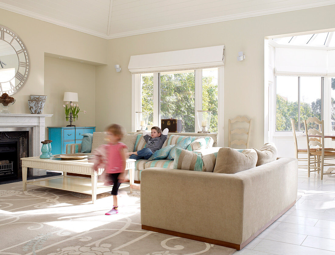 Children playing in bright, spacious lounge area with pastel blue, vintage chest of drawers