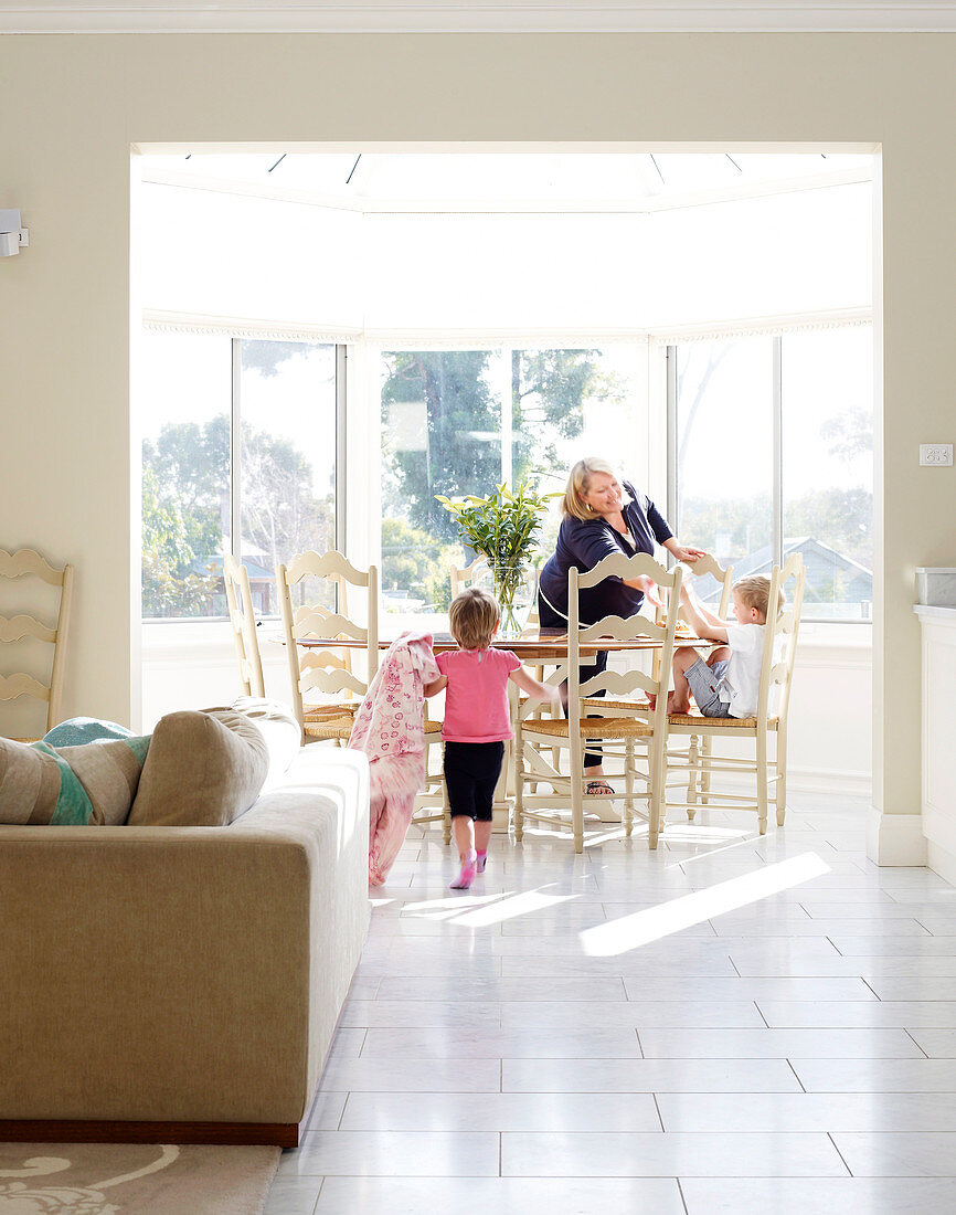 Mother and children in sunny dining room with panoramic windows