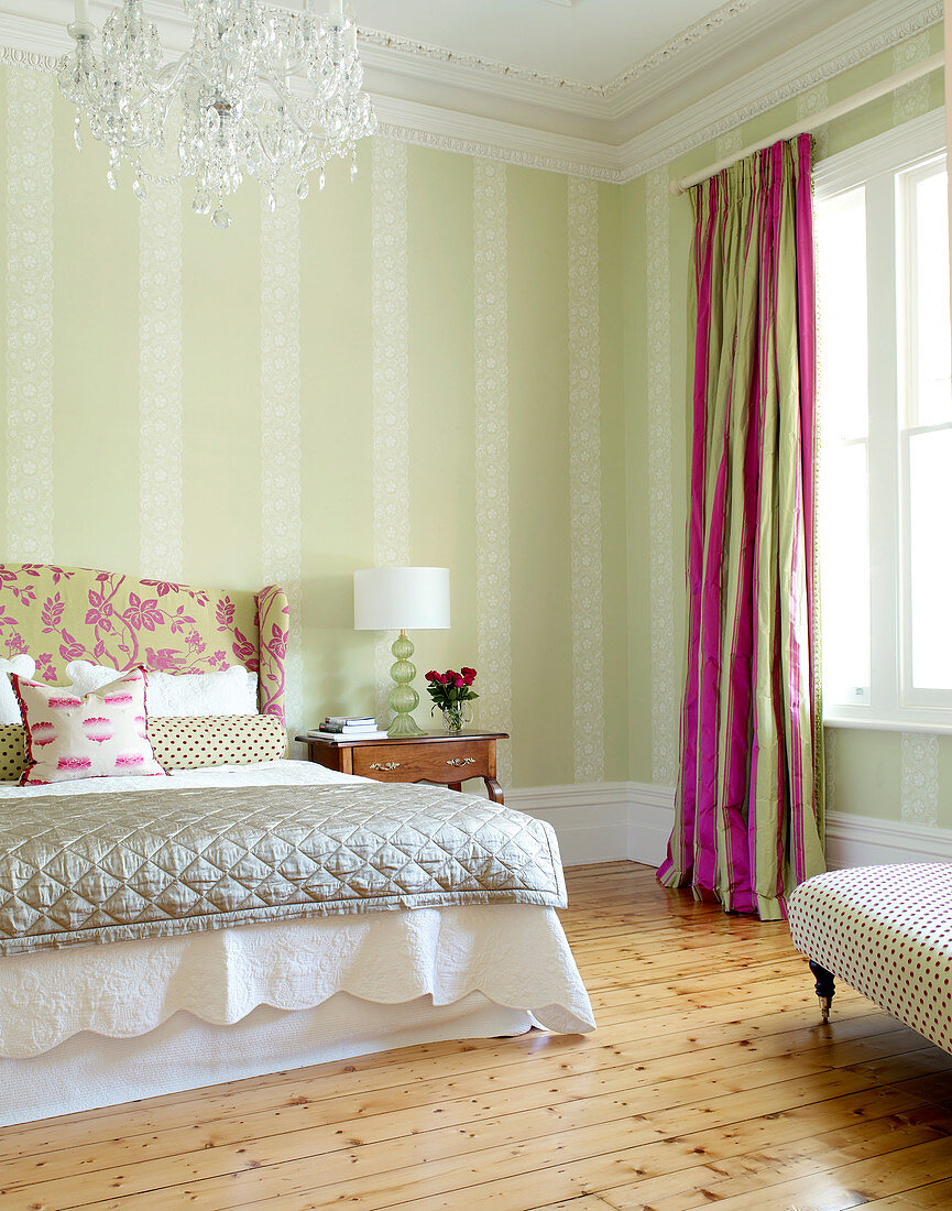Traditionelles Schlafzimmer in zarten Pastelltönen; pinkfarbene Akzente in Vorhängen und Bettkopfende sorgen für Fröhlichkeit