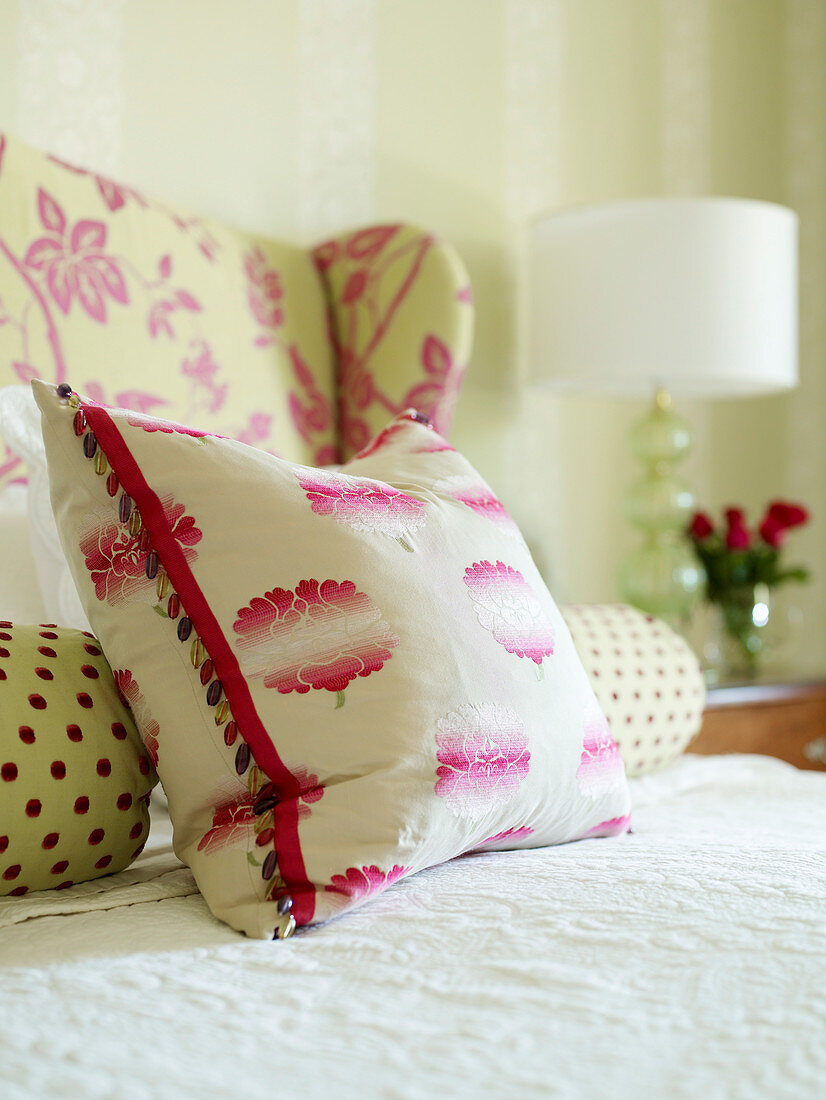 Bolster and decorative pillows in red and white on a bed with a white bedspread