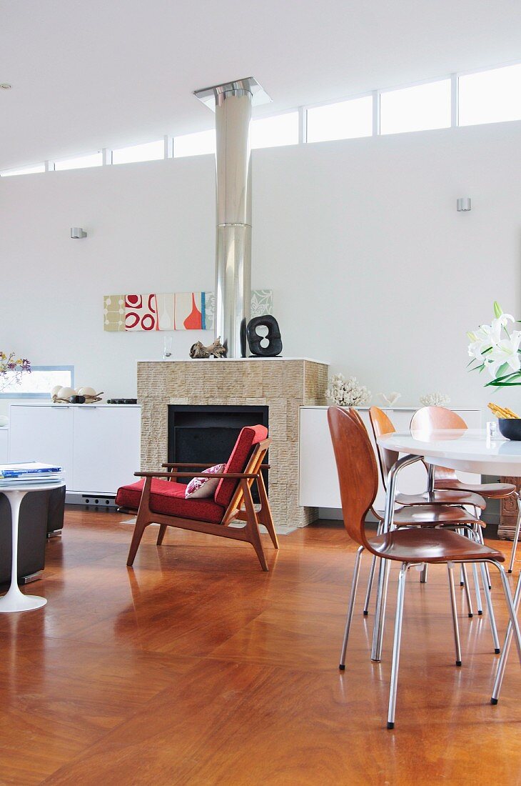 Sessel im 50er Jahre Stil vor Kamin und Essplatz in modernem offenem Wohnraum