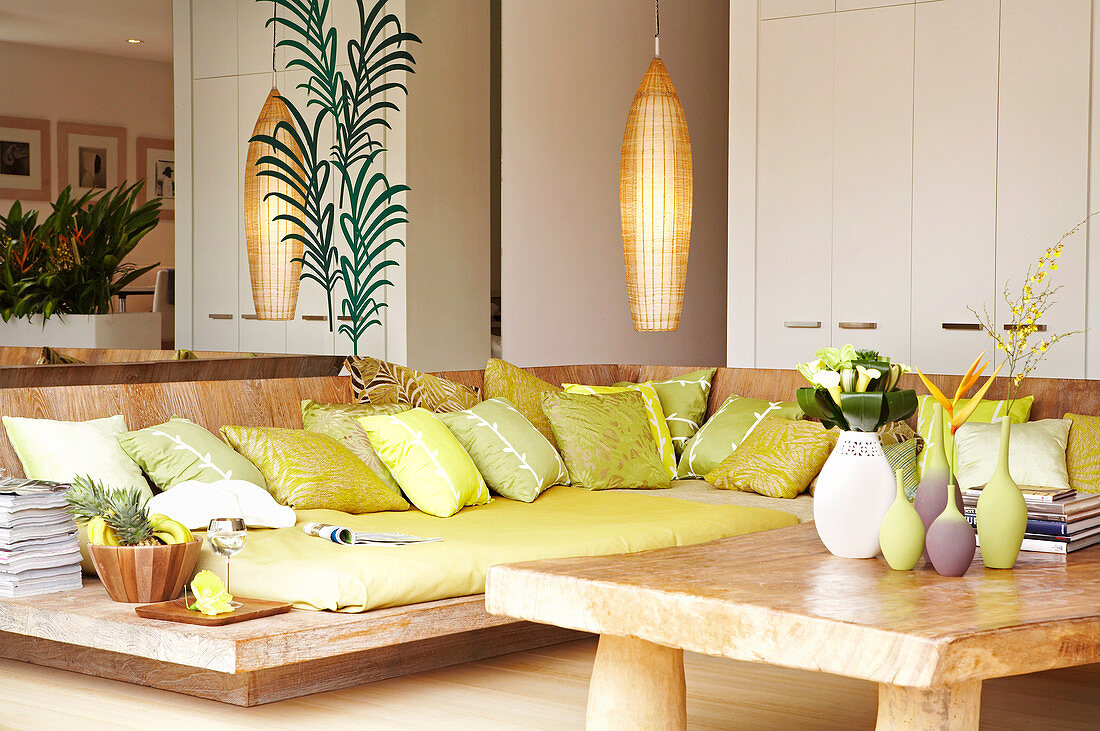 Loungeecke mit Polstern auf bodennahem Holzgestell und rustikaler Couchtisch in modernem Wohnzimmer