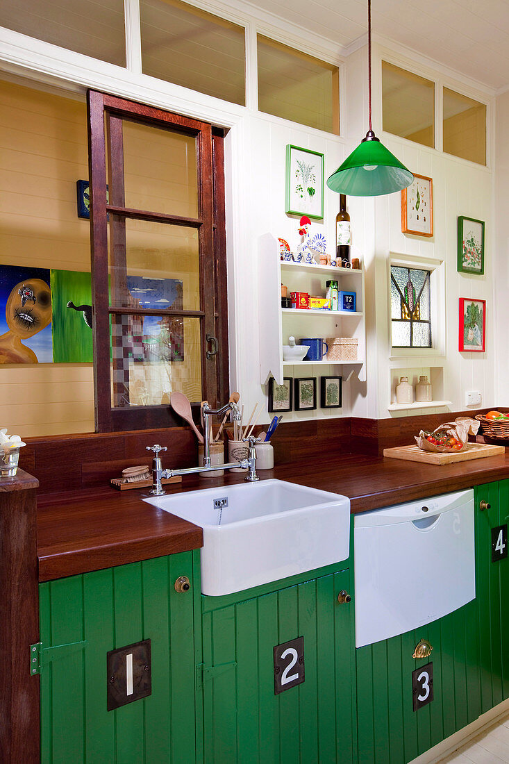 Retro Küche mit Holzarbeitsplatte und grün lackierten Unterschränken an Zimmerwand mit Oberlichtern