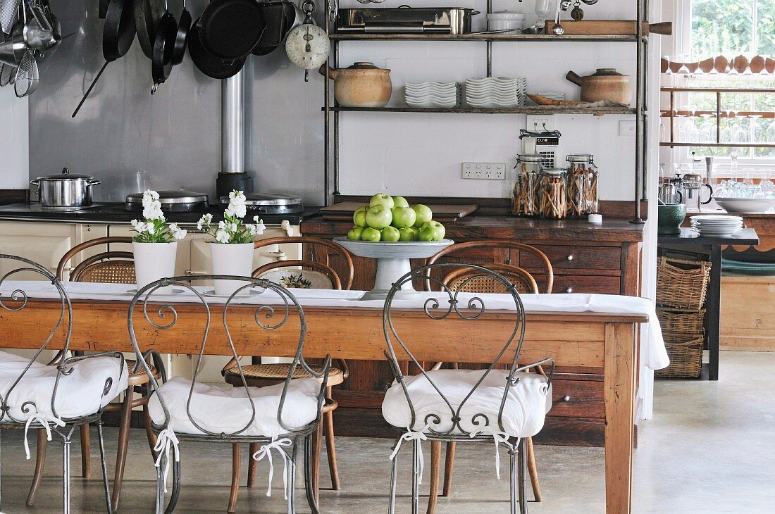 Long wooden kitchen table and chairs with curved metal frames in rustic kitchen