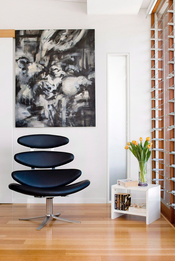 Retro designer armchair in front of modern artwork in corner of room