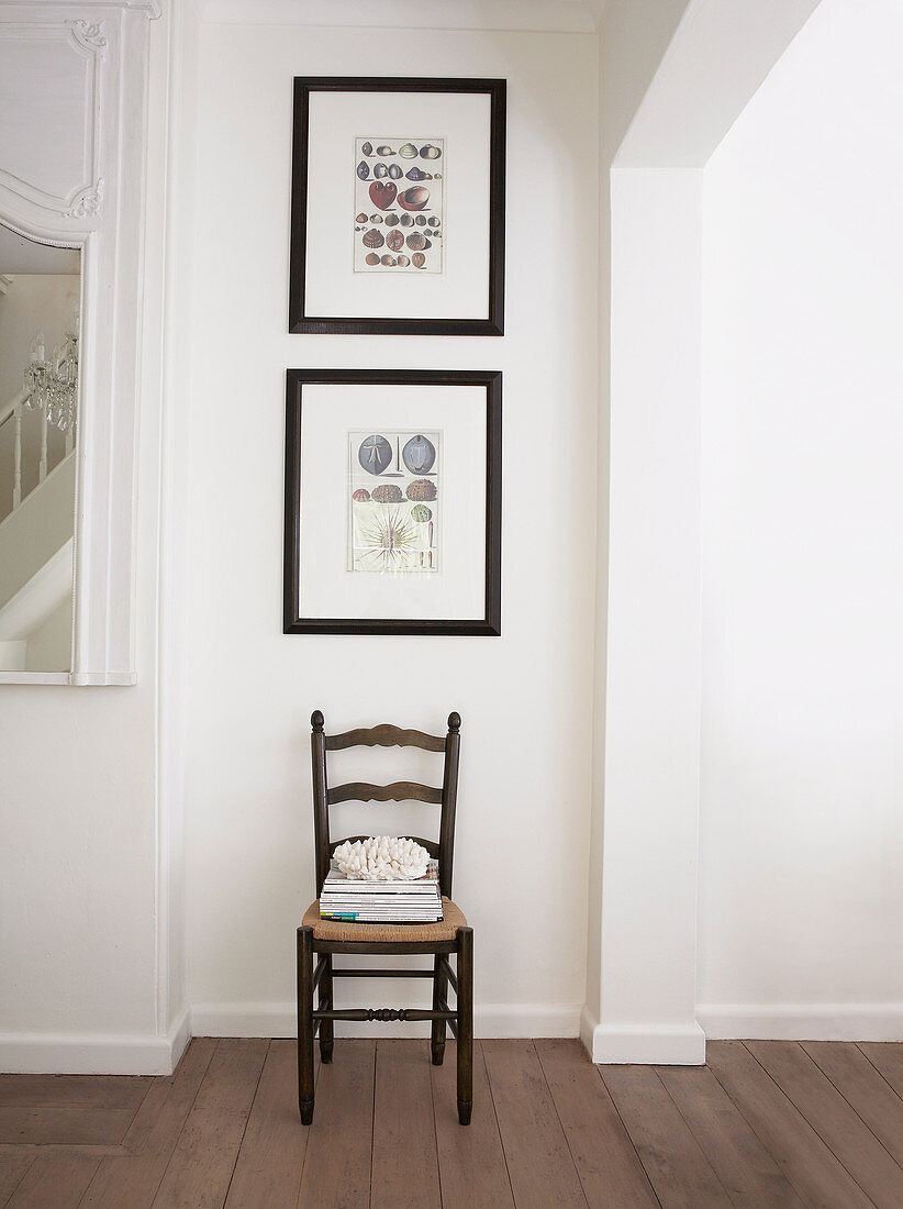 Framed pictures with maritime motifs on white wall above chair